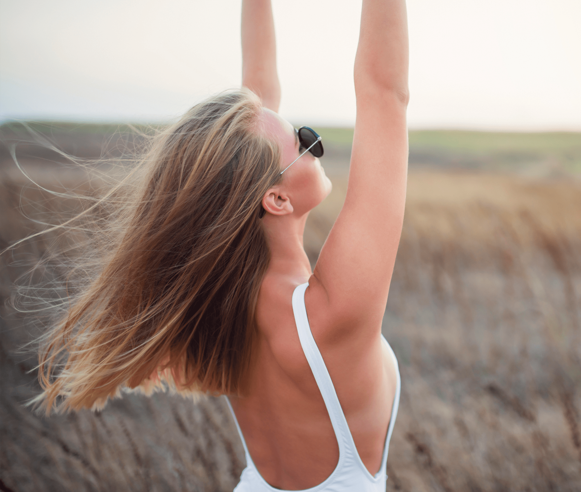 woman holding her arms up, hair blowing in the wind