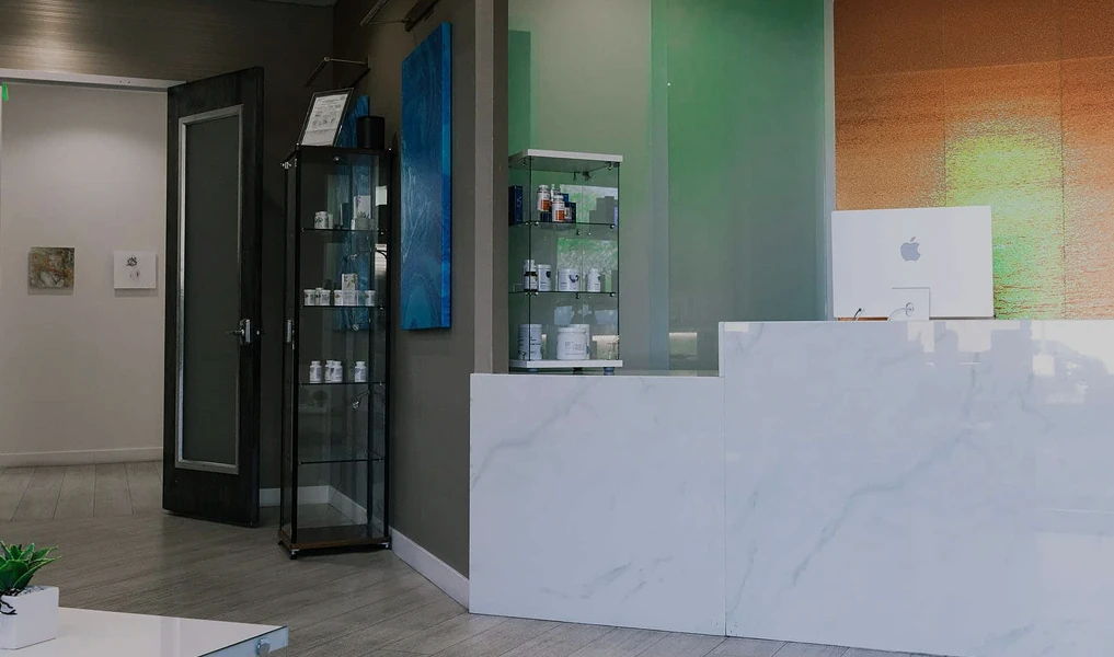 A photograph of a real-world office reception area featuring a marble-patterned front desk, a glass display case filled with skincare products, and modern art on the walls.