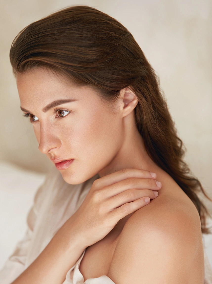 A side-profile portrait of a woman with long brown hair and clear skin. The focus is on her bright, almond-shaped eyes and the smooth, firm skin of the outer eye area. - Canthoplasty Canthopexy in Arizona