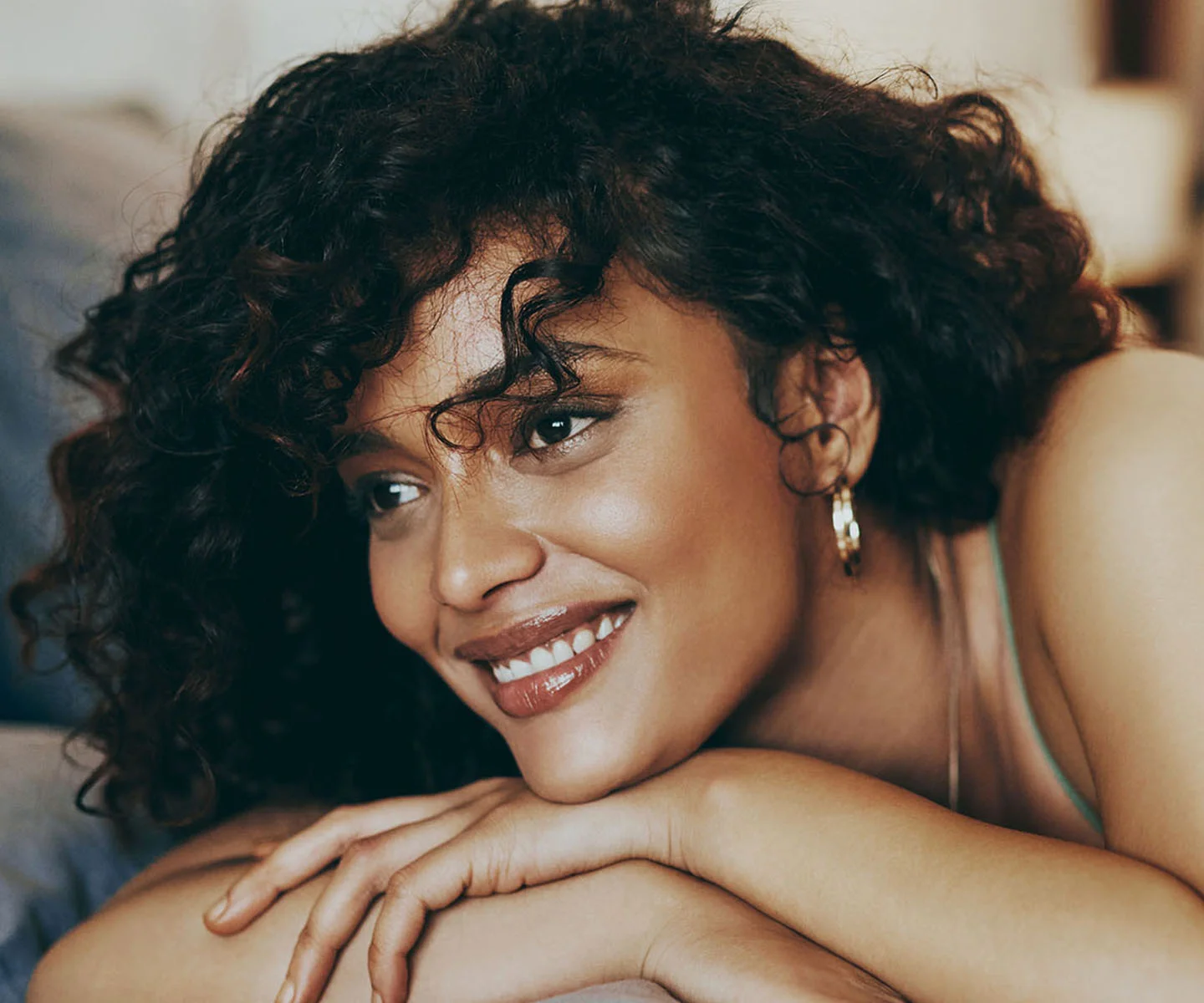 A close-up beauty portrait of a woman’s face in profile, showcasing a defined jawline and high cheekbones. Her skin is radiant and clear, and she has a neutral, elegant expression. The background is a soft, solid taupe color, ensuring the focus remains entirely on the structural features of her face and the sophisticated lighting. - Buccal fat removal in Arizona