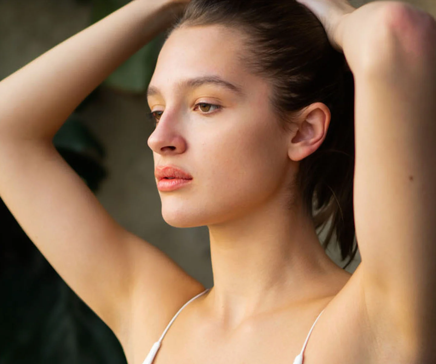 A detailed profile shot focusing on a woman’s ear and the side of her face. Her hair is tucked neatly behind her ear, and she wears a subtle, calm expression. The image is brightly lit with a clean, soft-focus background in shades of off-white and cream, emphasizing clarity and a polished, natural appearance. - Earlobe closure in Arizona