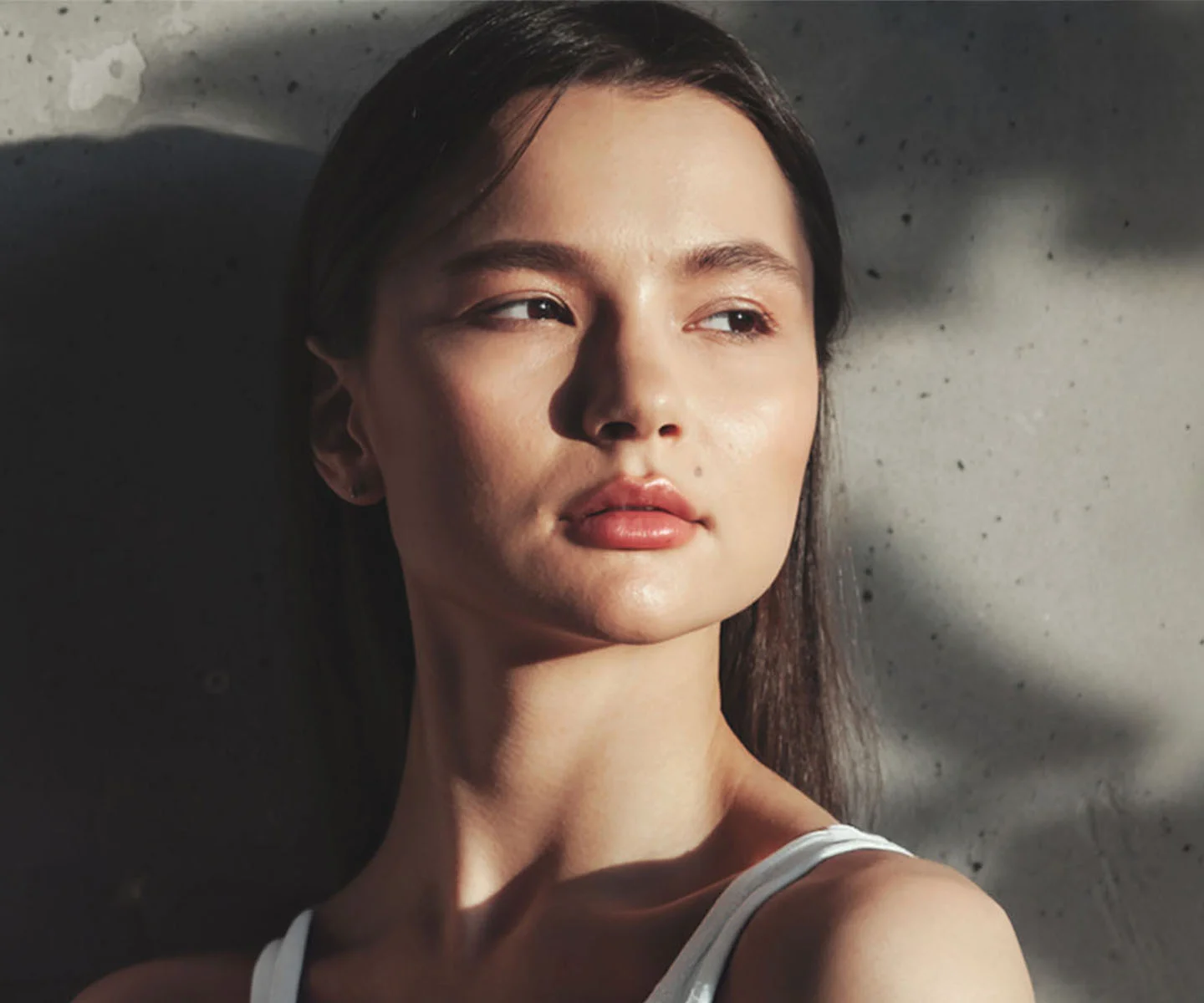 A sophisticated profile portrait of a woman with a strong, defined facial structure. She is looking forward with a confident gaze. The lighting is strategically placed to highlight the bridge and tip of her nose and the contours of her cheekbones. The background is a solid, muted grey-brown, creating a high-end, professional look. - Ethnic rhinoplasty in Arizona