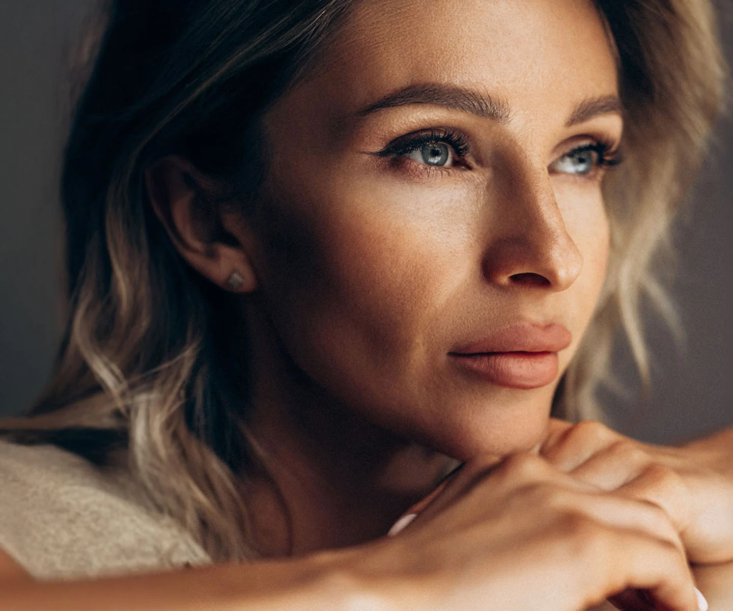 A close-up, high-detail portrait of a woman with blonde hair looking upward. The focus is on her bright, youthful eyes and smooth upper and lower eyelid contours, showcasing a rested and rejuvenated appearance. - Eyelid Surgery in Arizona