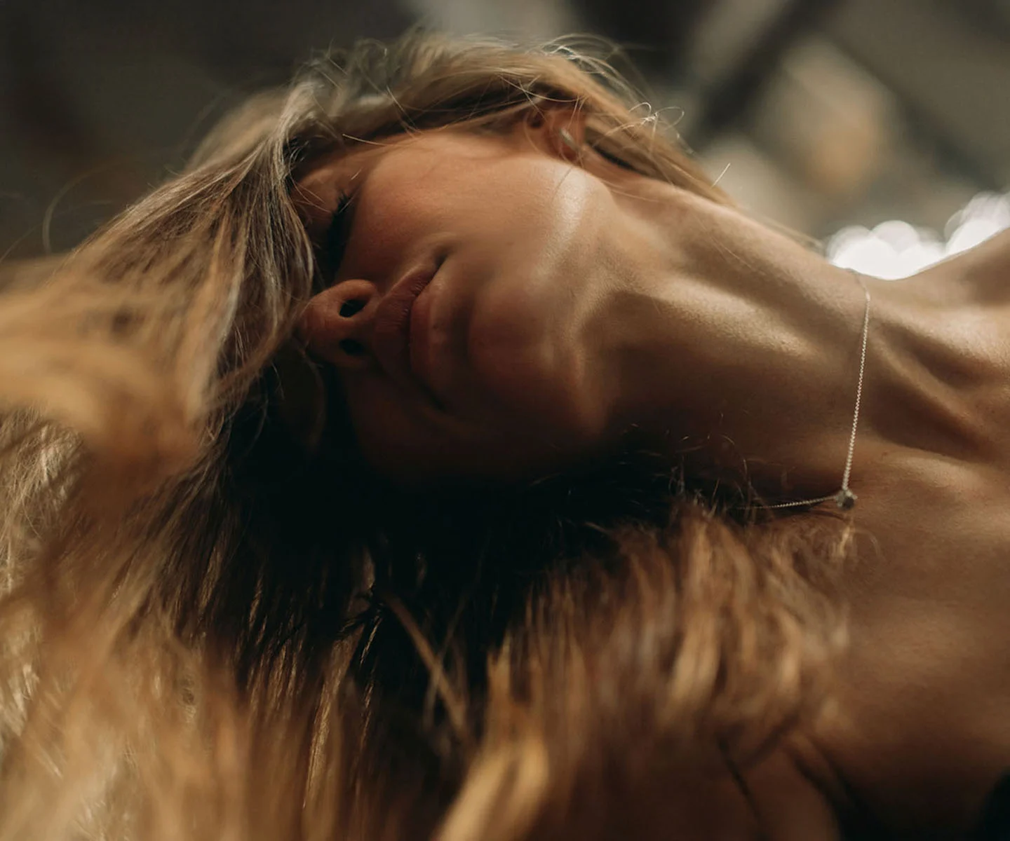 A low-angle, artistic shot of a woman looking down, focusing on the refined and contoured transition between the jawline and the neck, accented by a delicate silver necklace. - Myellevate in Arizona