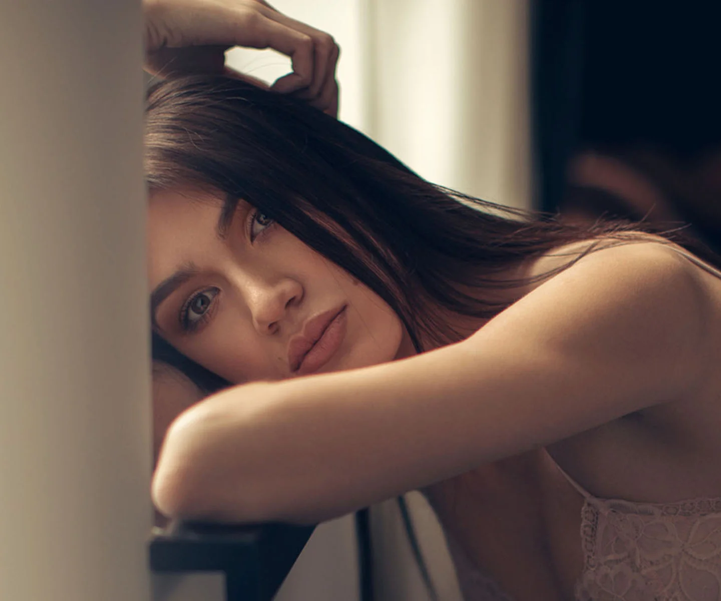 A close-up of a woman resting her head on her arms, looking calmly into the lens. The soft-focus background and intimate composition represent the care and detail involved in the patient journey. - The Process in Arizona